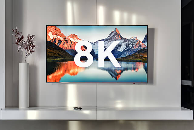 An der Wand montierter Fernseher, der „8K” über einem malerischen Berg- und Seebild anzeigt und auf Ultra-High-Definition-Streaming hinweist.