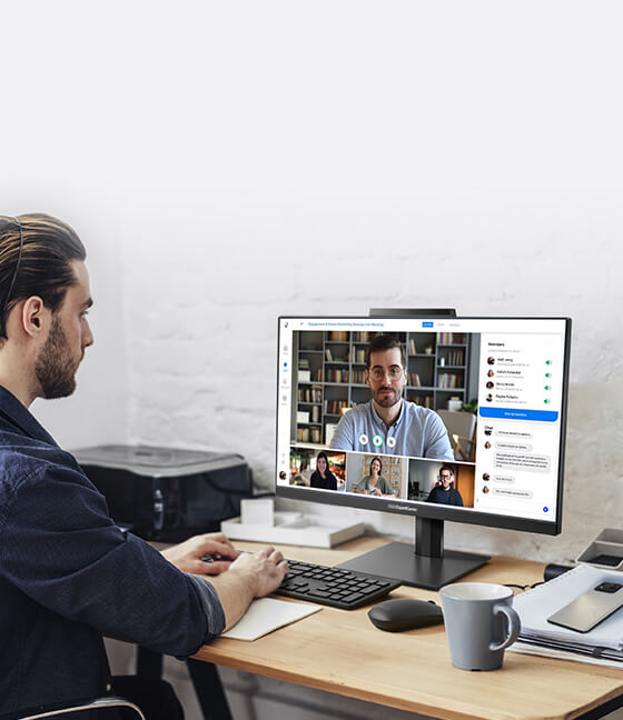 Un hombre trabaja a distancia utilizando un ordenador de sobremesa para una llamada de videoconferencia.