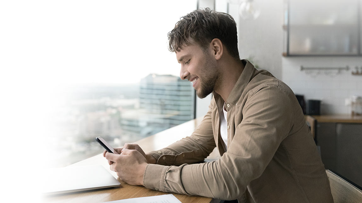 Een man zit in een café en gebruikt zijn mobiel