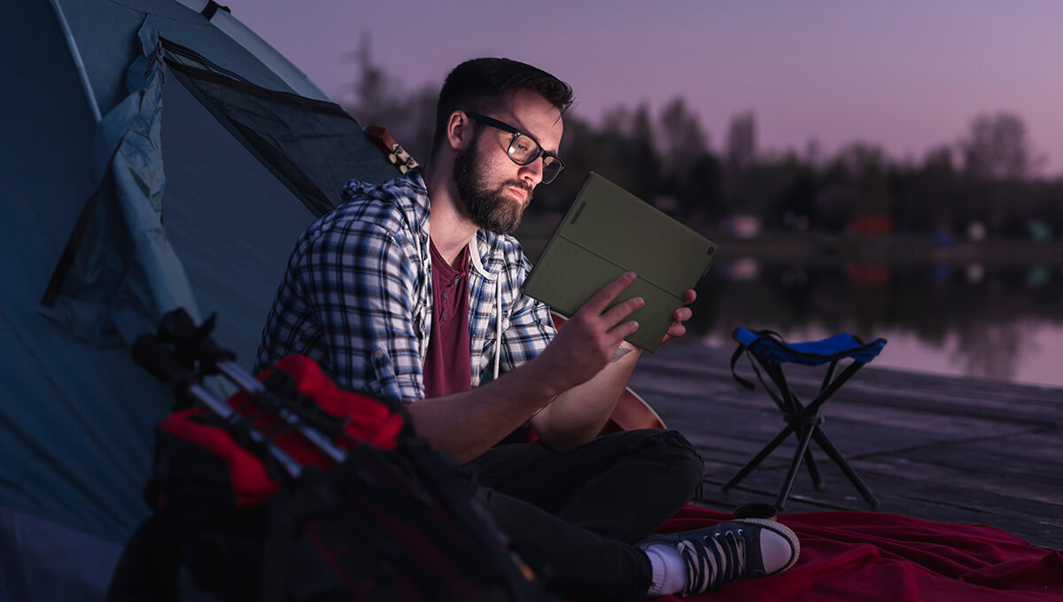 a content creator sitting in front of a tent, holding a ProArt PZ13 device in hands