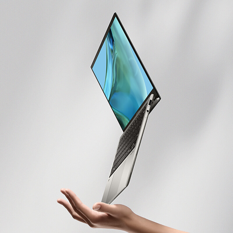 An open ASUS Zenbook S 13 OLED balancing on a hand on a corner of the laptop’s lower half.