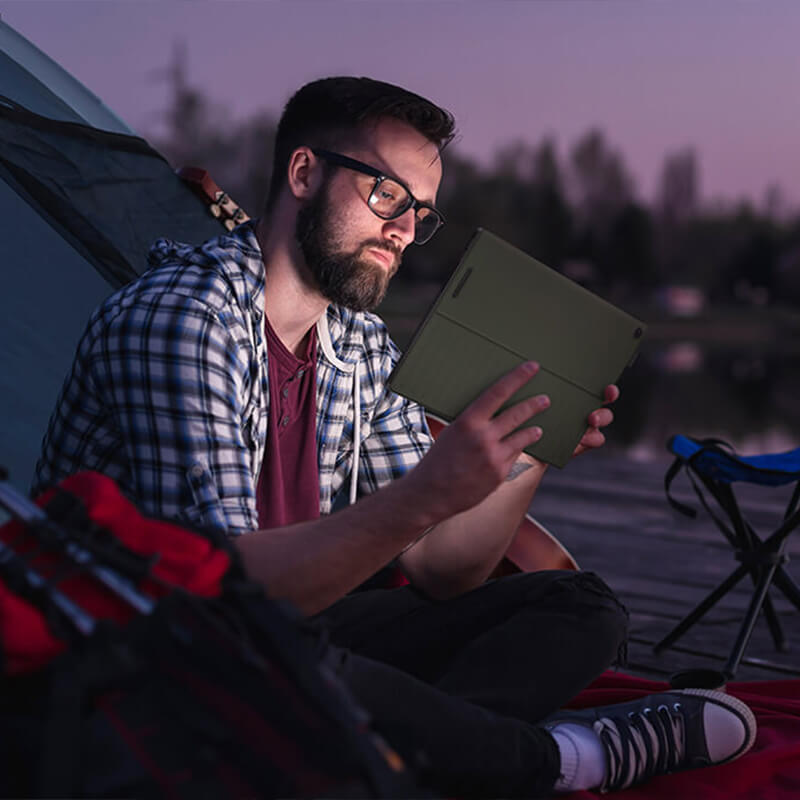 a content creator sitting in front of a tent, holding a ProArt PZ13 device in hands