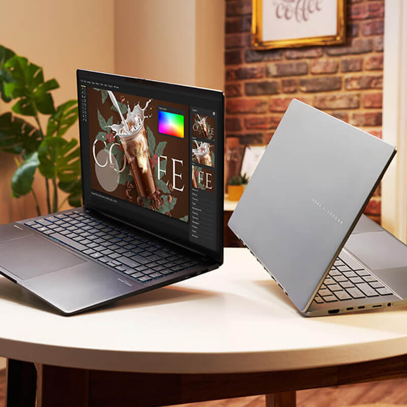 Two ASUS Vivobooks tilted slightly and hovering on a round coffee table.