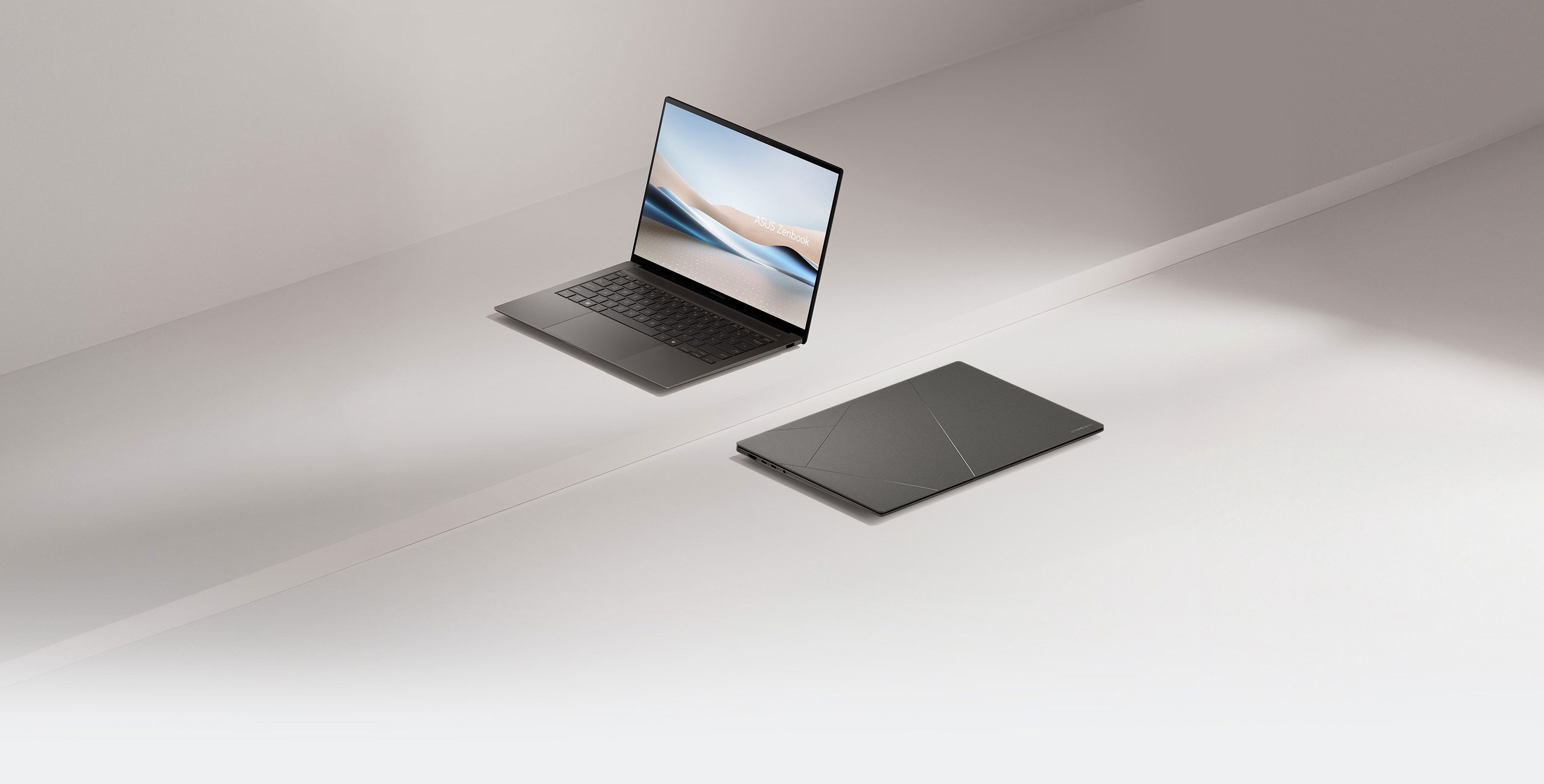 Two Zenbook S 14, one of them opened at 100 degrees and viewed from the left front, while the other one is closed and placed on the ground.