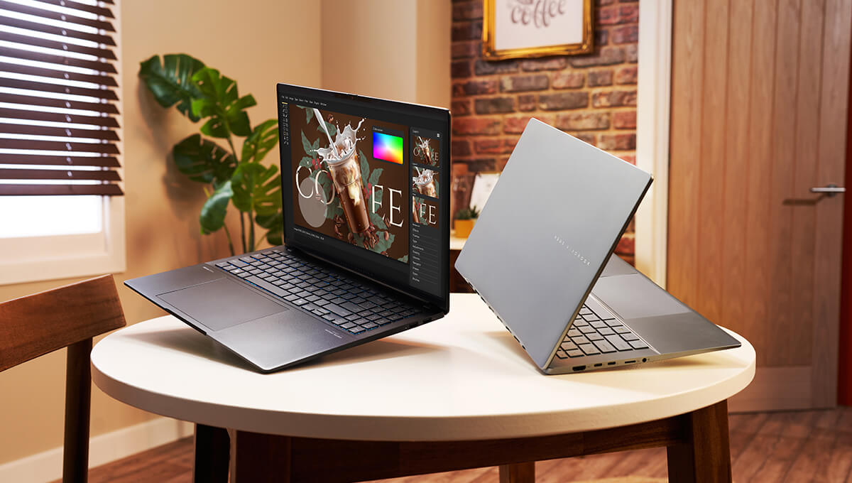 Two ASUS Vivobooks tilted slightly and hovering on a round coffee table.