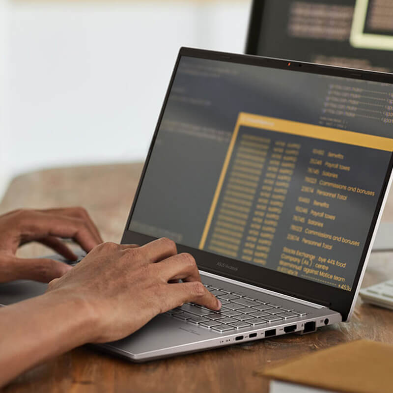 A man using an ASUS laptop and an external display for work.