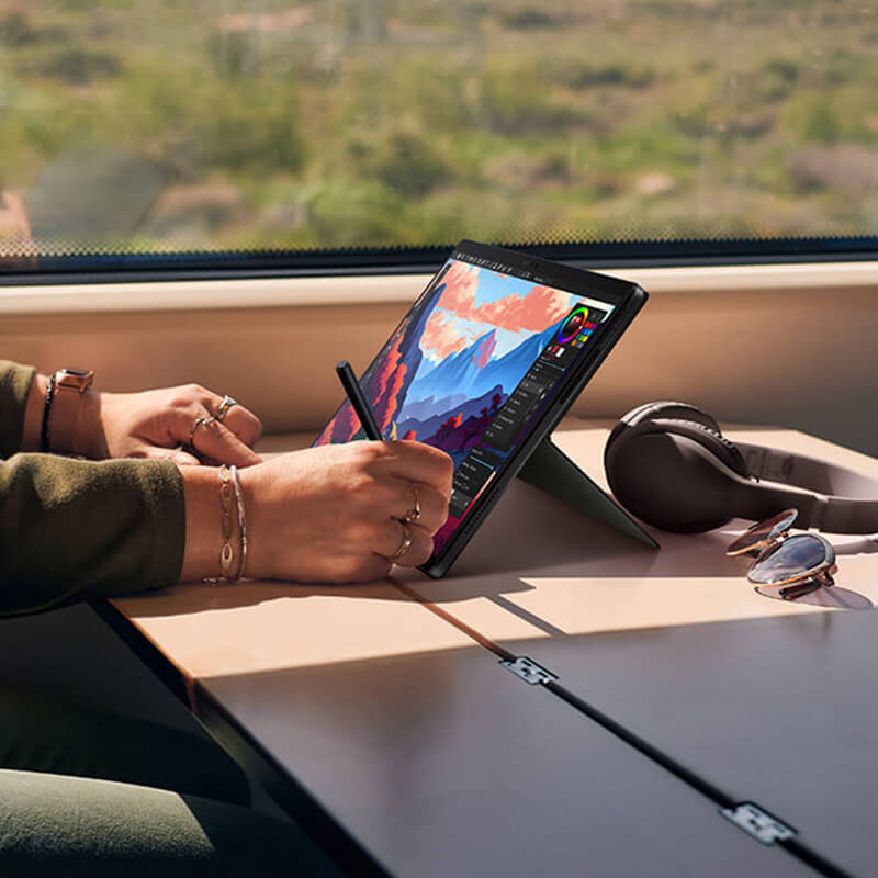 a content creator editing an image by using a stylus on the ProArt PZ13 laptop-and-tablet device on a table on a train