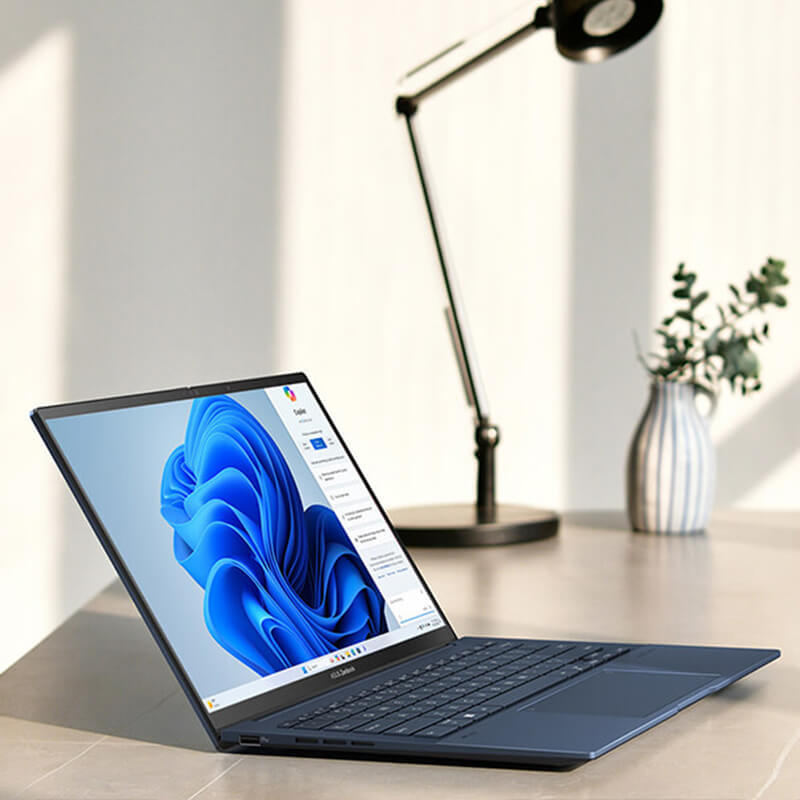 ASUS Zenbook 14 OLED sitting on a stone desk with Microsoft Copilot displayed on the screen